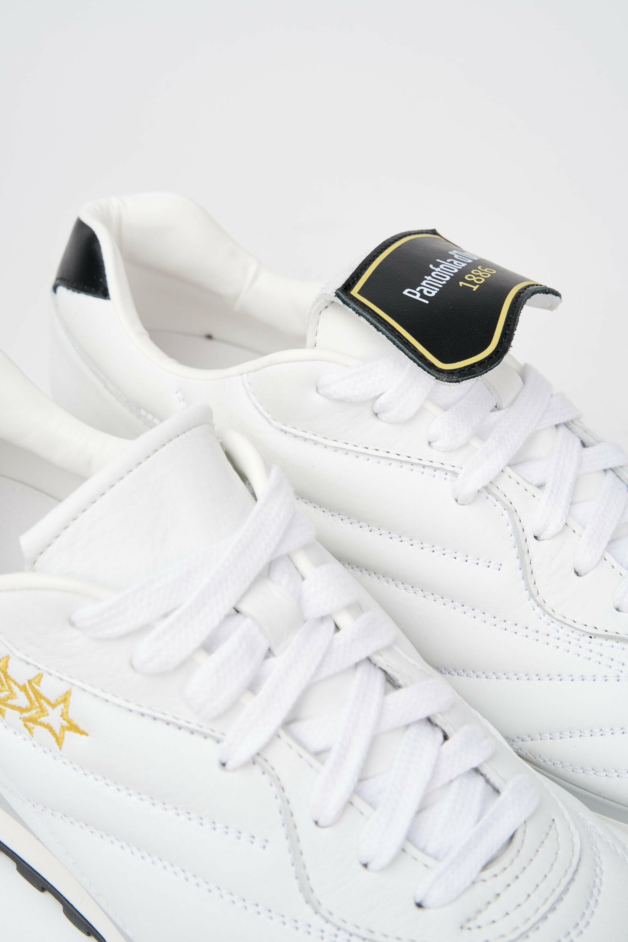 Sneakers uomo Pitch in pelle bianca e nera con stelle cucite oro.